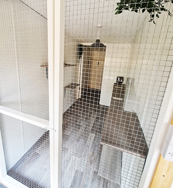 interior view through wire mesh door showing modern kitchen and living space with light wood flooring and neutral decor six design elements for efficient living